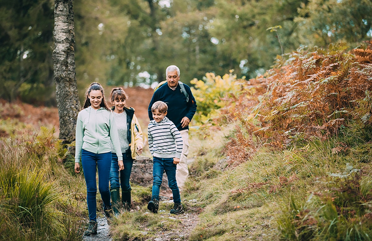 Grandparents hiking an autumn woodland trail with grandchildren, enjoying active retirement in Alberta