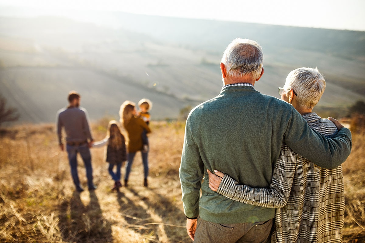 Grandparents watching grandchildren play outdoors, confident in retirement health and travel coverage