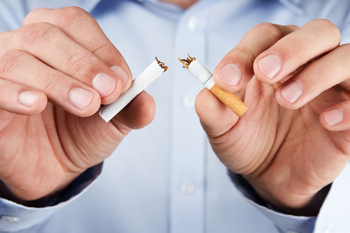 Hands breaking a cigarette in half, symbolizing quitting smoking with ASEBP MyRetiree Plan prescription drug coverage