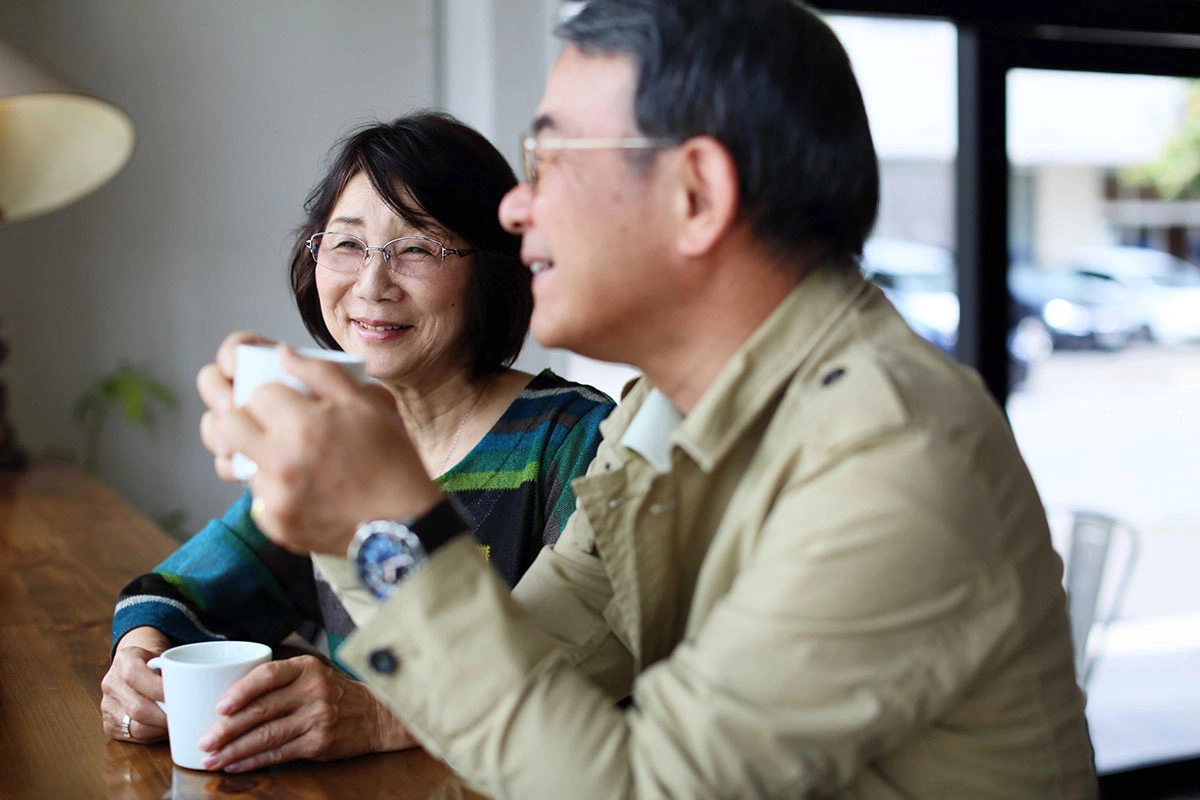 Retired couple enjoying coffee together at a café, representing active social life in retirement with ASEBP MyRetiree Plan coverage